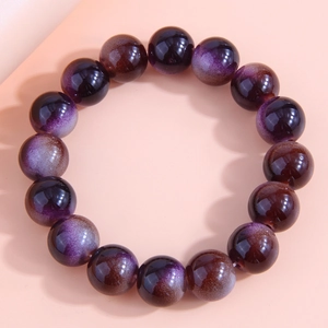 Macro shot of stylish gradient coffee and purple glass beaded bracelet on pink surface