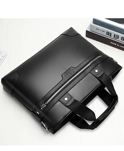 Detail view of black leather business briefcase with embossed logo on a white wooden table