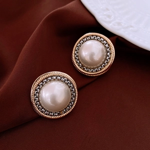 Macro detail of vintage round pearl earrings with gold twisted rope and silver chain borders