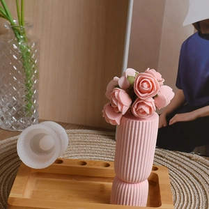 Macro view showing a cylinder silicone mold next to a pink textured plaster vase