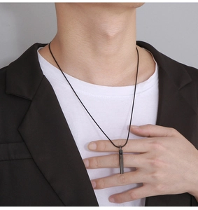 Close-up of minimalist black bar pendant necklace worn with a brown blazer