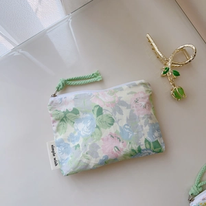 Détail de la pochette en coton à fleurs avec fermeture éclair et étiquette tissée