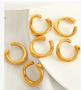 Detailed view of five minimalist gold ear cuffs arranged on a white textured background