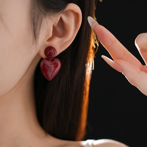 Close-up of heart-shaped red pendant earring worn by a model in soft side lighting