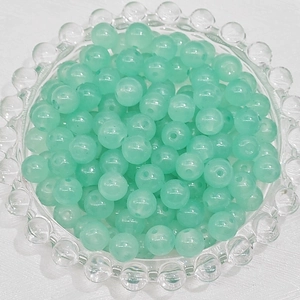 Macro shot of 4-8mm pale green round glass beads in a decorative tray for DIY jewelry