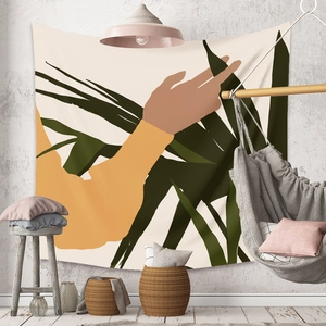 Macro view of abstract tapestry showing hand touching tropical leaves on a white wall
