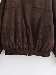Macro view of brown suede jacket showing elastic pleated hem detail and stitching