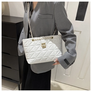 Detail showing white quilted tote bag with golden chain strap and metallic buckle