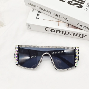 Détail de lunettes de soleil noires avec strass argentés sur textile blanc