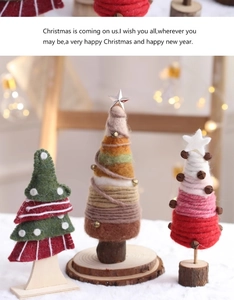 Detail of handcrafted wool felt Christmas trees with warm string lights and wooden base