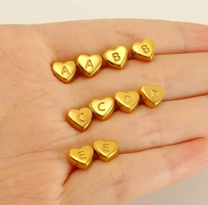 Golden heart-shaped stainless steel beads with engraved letters A to E held in palm
