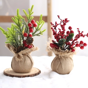 Miniature Christmas trees with red berries and pine cones in burlap bases for desk decor