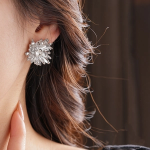 Detailed view of flower earrings with sparkling crystals worn on a model's ear