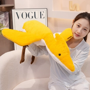Close-up of a soft yellow pterosaur plush toy pillow being held by a model
