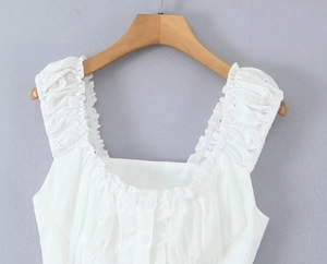 Detail of white ruffle sleeveless top with embroidery eyelet and button front