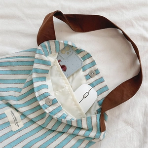Detail of striped canvas tote bag showing magnetic snap closure and inner pocket