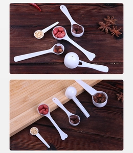 Various sizes of white plastic measuring spoons displayed with spices on a wooden background