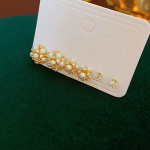 Dettaglio macro di orecchini vintage a fiore dorati con perle e piccoli strass