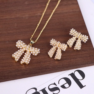 Detail view of pearl bowknot necklace and earrings set on dark wooden surface