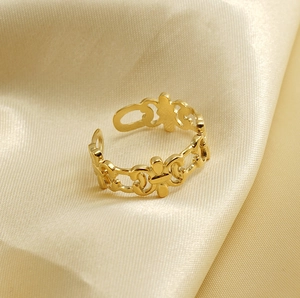 Detailed macro view of 18K gold hollow floral ring on beige silk background