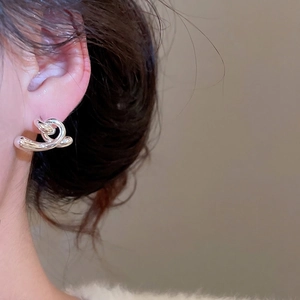 Boucles d'oreilles minimalistes en argent avec fini poli portées par un mannequin