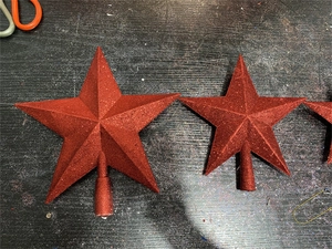Detailed view of three red star tree toppers in various sizes with glitter finish