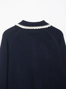 Close-up of knit sweater collar featuring elegant cream crochet wavy lace trim details