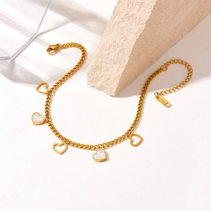 Detail of gold stainless steel anklet with white shell heart charms on a stone base