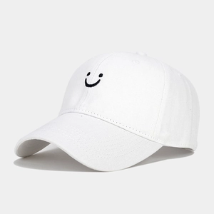 Close-up of black embroidered smiley face on a white cotton canvas baseball cap