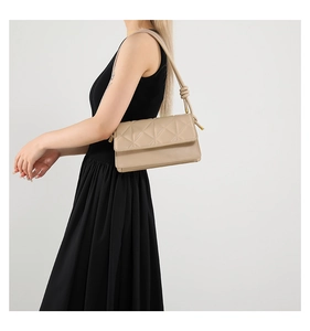 Detail of beige square handbag with geometric diamond embossing and knotted strap