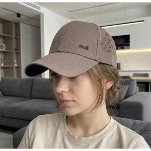 Close-up of brown breathable baseball cap with metal sports tag and ventilation holes