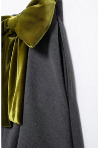 Détail du nœud en velours vert olive sur le tissu gris foncé de la mini-jupe