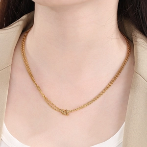 Detail of a double-layered gold rope chain necklace with a central knot on a model