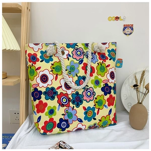 Detailed view of floral canvas tote bag with thick white woven rope handles on wood shelf