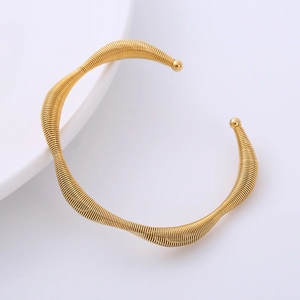 Detail of 18K gold wave bangle showing spring texture and smooth bead ends close-up