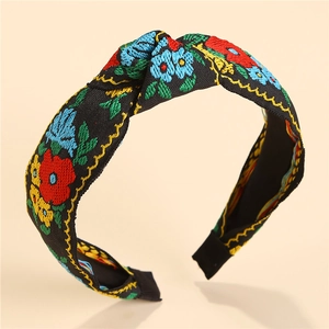 Close-up of floral embroidery on a black knotted headband with vintage folk style patterns