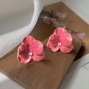 Detailed close-up of pink enamel floral earrings with a sparkling zircon center stone