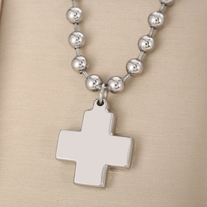 Detailed view of a shiny silver cross pendant on a heavy stainless steel bead chain
