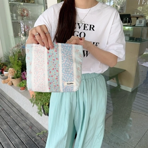 Close-up of floral print cotton makeup bag held by a model in casual setting