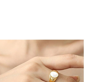 Macro detail of gold irregular ring featuring oval white gemstone on model's hand