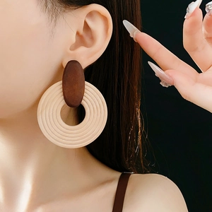 Gros plan de boucles d'oreilles créoles géométriques en bois marron et ivoire texturé
