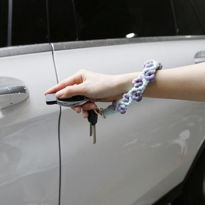 Detail of handmade crochet flower wristlet keychain in lavender and blue on a car door