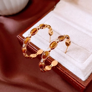 Détail de boucles d'oreilles créoles en C plaquées or 18k avec gemmes brunes et cristaux