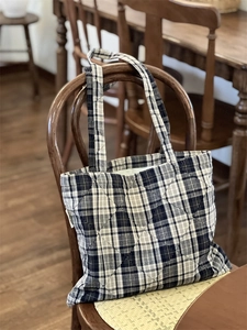 Detailed diamond quilting and classic blue plaid pattern on a cotton shoulder bag