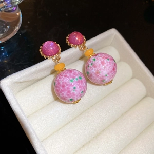 Detailed close-up of vintage resin pink spotted orb earrings in a jewelry box display