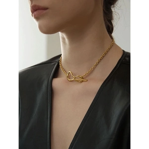 Macro detail of a minimalist gold chunky chain necklace with a stylish knot clasp on model