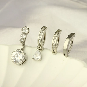 Set of silver stainless steel navel rings with clear zircon stones on a shell