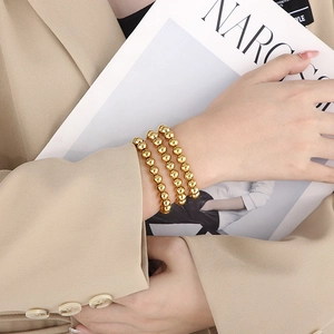 Detailed close-up of a three-piece gold beaded stretch bracelet set on a female wrist