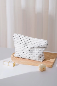Dettaglio della borsa da trucco minimalista a pois su un vassoio di legno