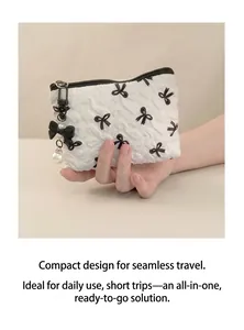 Detail of white quilted makeup bag with black bow patterns and pearl charm accessory